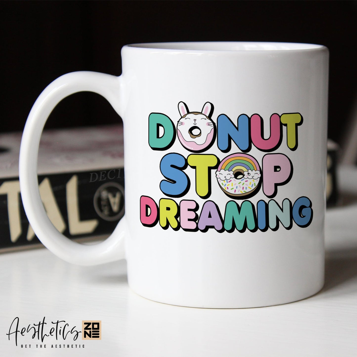White mug with colorful text 'Donut Stop Dreaming' on a blurred background