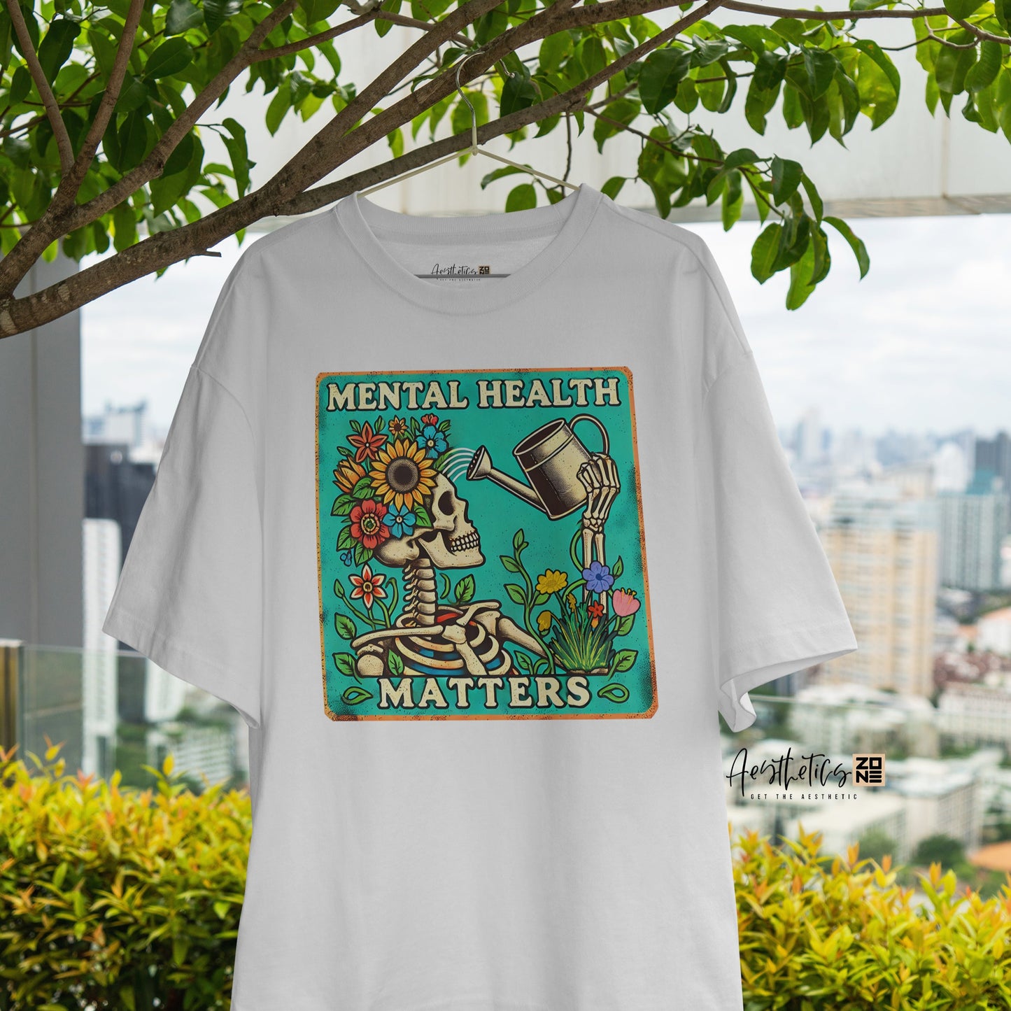 White t-shirt with 'Mental Health Matters' design hanging outdoors with greenery and cityscape in the background