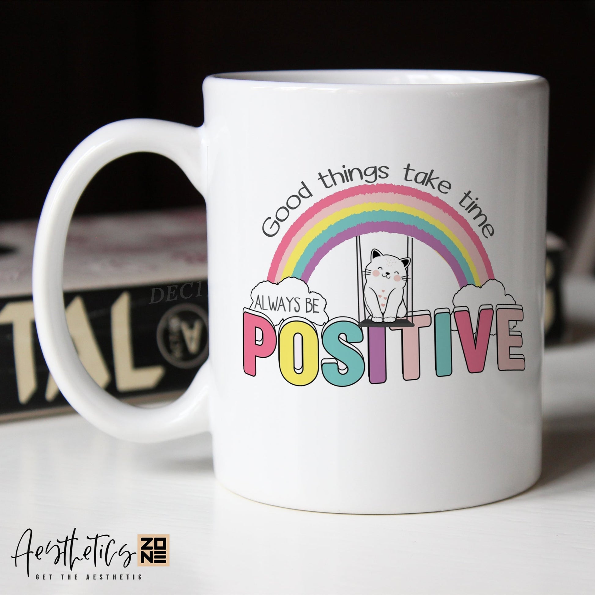 White coffee mug with motivational quote and rainbow design on a blurred background