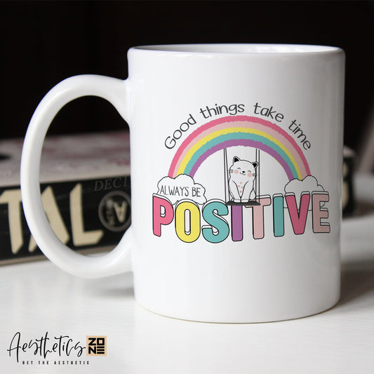 White coffee mug with motivational quote and rainbow design on a blurred background