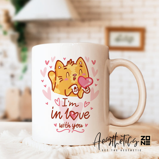 Mug with a cartoon cat holding a heart and text 'I'm in love with you' on a blurred background.