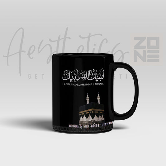 Black mug with white Arabic text and Kaaba design on a light gray background