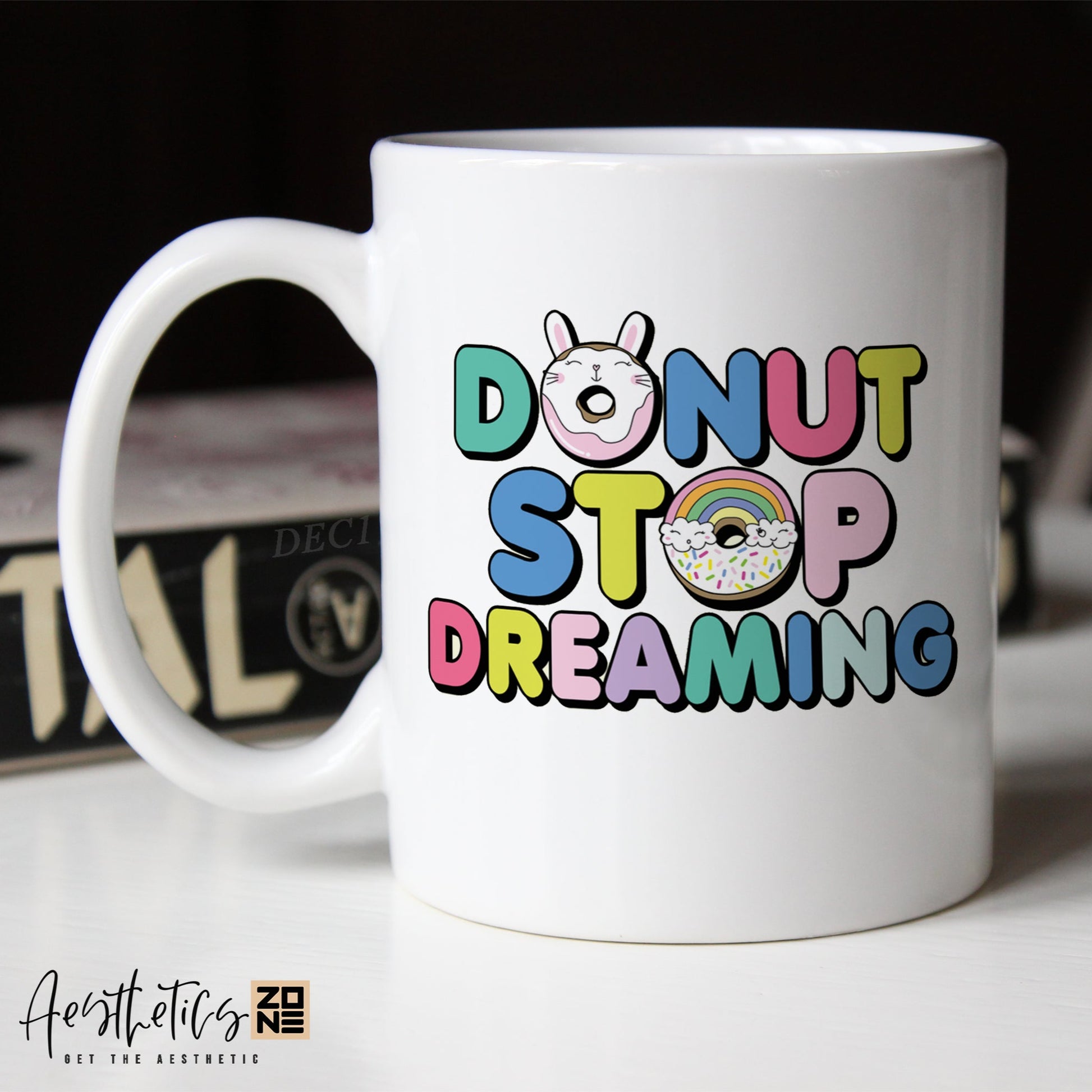 White mug with colorful text 'Donut Stop Dreaming' on a blurred background