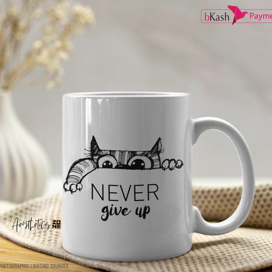 White mug with a cat design and 'Never give up' text on a wooden surface with a blurred background.