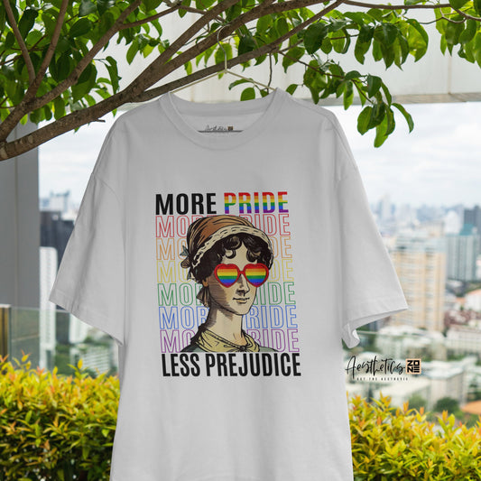 White t-shirt with a graphic design featuring text and a rainbow flag, hanging outdoors with greenery and a cityscape in the background.