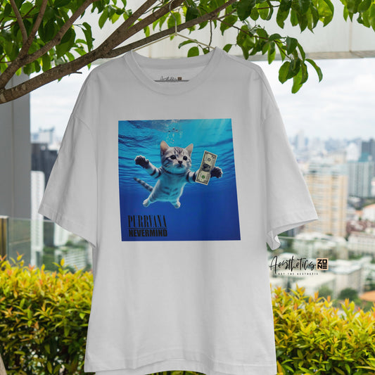 White t-shirt with a graphic of a cat in water and text, hanging outdoors with greenery and a cityscape in the background.