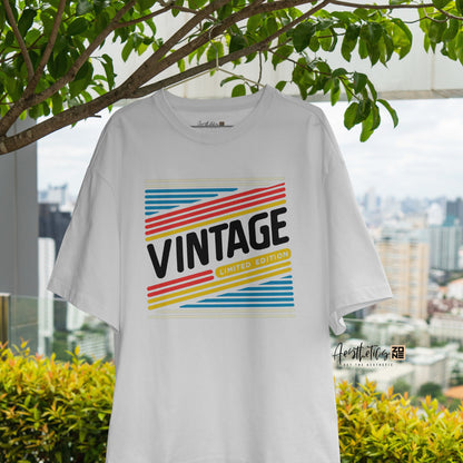 White t-shirt with 'Vintage' design hanging outdoors with greenery and cityscape in the background